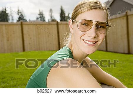 Portrait of a young woman sitting on a lawn View Large Photo Image Stock Photo - Portrait of a young woman sitting on a lawn. Fotosearch