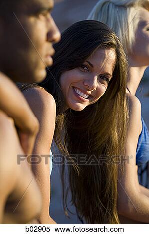 Portrait of a young woman sitting with friends View Large Photo Image Stock Photography - Portrait of a young woman sitting with friends. Fotosearch