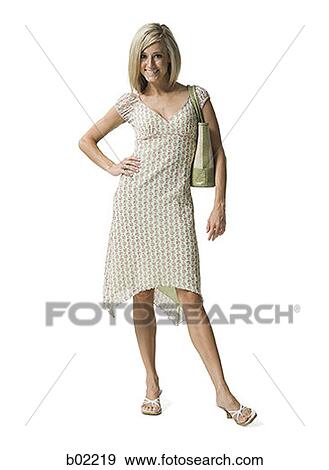 Portrait of a young woman standing and holding a purse View Large Photo Image Stock Photo - Portrait of a young woman standing and holding a purse. Fotosearch
