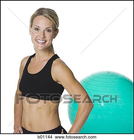 Portrait of a young woman standing in front of an exercise ball View Large Photo Image Picture - Portrait of a young woman standing in front of an exercise ball. Fotosearch
