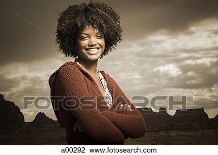 Stock Image - Portrait of a young woman standing with her arms crossed. Fotosearch