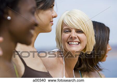 Portrait of a young woman standing with three women, smiling View Large Photo Image Stock Image - Portrait of a young woman standing with three women, smiling. Fotosearch