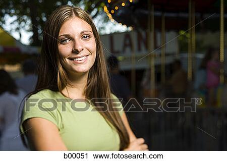 Portrait of a young woman standing with her arms crossed at a carnival View Large Photo Image Stock Image - Portrait of a young woman standing with her arms crossed at a carnival. Fotosearch