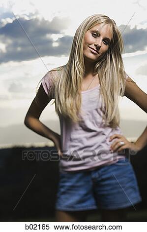 Stock Photography - Portrait of a young woman standing with her hands on her hips. Fotosearch