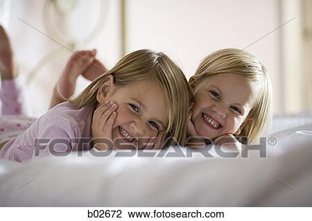 Portrait of two sisters lying on the bed View Large Photo Image Stock Image - Portrait of two sisters lying on the bed. Fotosearch