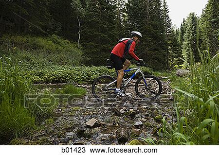 Profile of a mature man cycling over a creek View Large Photo Image Stock Image - Profile of a mature man cycling over a creek. Fotosearch