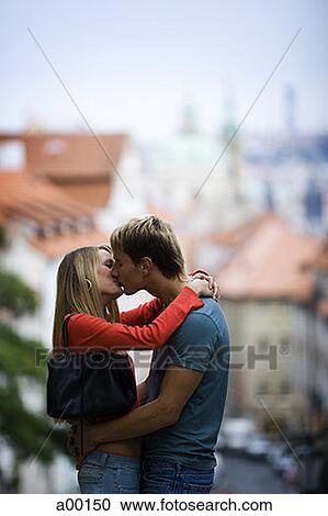 Stock Image - Profile of a young couple kissing outdoors. Fotosearch
