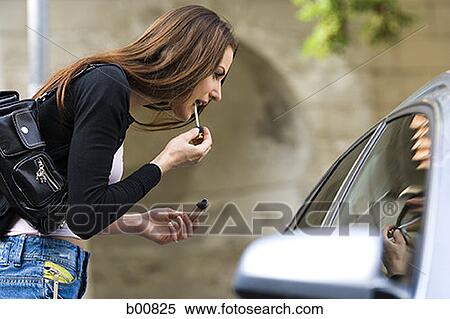 Profile of a young woman applying lipstick View Large Photo Image Stock Photography - Profile of a young woman applying lipstick. Fotosearch