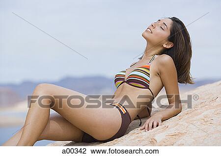 Stock Image - Profile of a young woman lying on a rock. Fotosearch