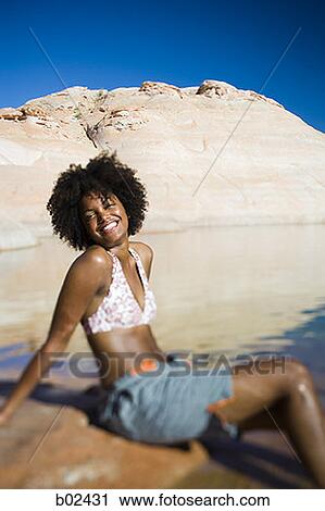 Profile of a young woman sitting on a rock and smiling View Large Photo Image Stock Image - Profile of a young woman sitting on a rock and smiling. Fotosearch
