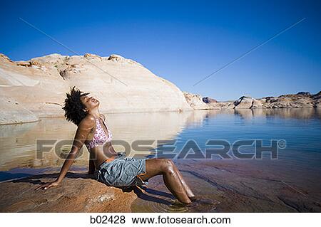 Profile of a young woman sitting on a rock with her eyes closed View Large Photo Image Stock Photo - Profile of a young woman sitting on a rock with her eyes closed. Fotosearch