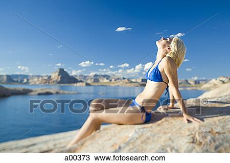 Stock Image - Profile of a young woman sitting, lakeside. Fotosearch