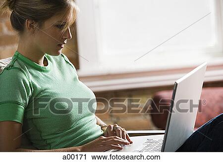 Stock Image - Profile of a young woman using a laptop. Fotosearch