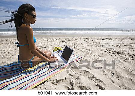 Profile of a young woman using a laptop on the beach View Large Photo Image Stock Image - Profile of a young woman using a laptop on the beach. Fotosearch