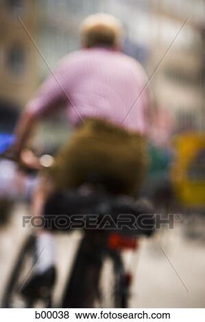 Rear view of a man riding a bicycle View Large Photo Image Stock Photo - Rear view of a man riding a bicycle. Fotosearch