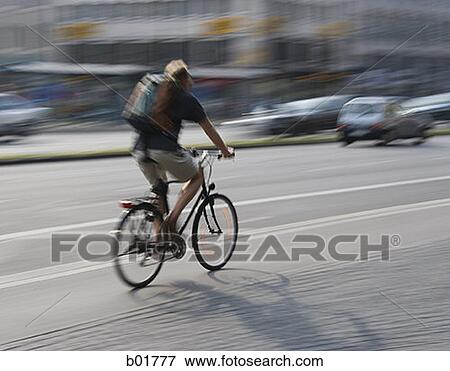 Rear view of a man riding a bicycle View Large Photo Image Stock Photo - Rear view of a man riding a bicycle. Fotosearch