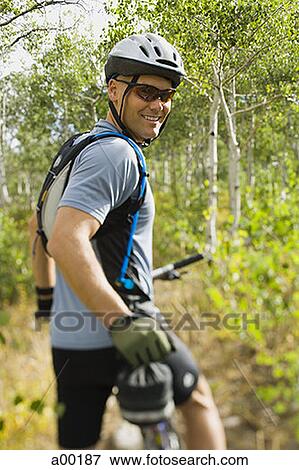 Stock Photo - Rear view of a mature man mountain biking. Fotosearch