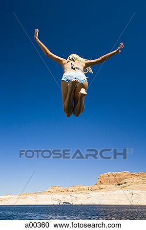 Rear view of a young woman jumping into a lake View Large Photo Image Stock Image - Rear view of a young woman jumping into a lake. Fotosearch