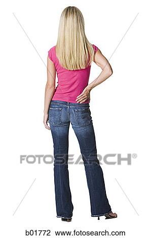 Rear view of a young woman standing with her hand on her hip View Large Photo Image Stock Image - Rear view of a young woman standing with her hand on her hip. Fotosearch