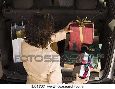 Rear view of an adult woman holding wrapped gift boxes View Large Photo Image Stock Photo - Rear view of an adult woman holding wrapped gift boxes. Fotosearch