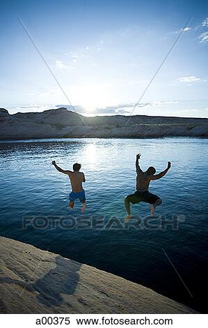 Rear view of two men jumping into a lake View Large Photo Image Stock Photography - Rear view of two men jumping into a lake. Fotosearch