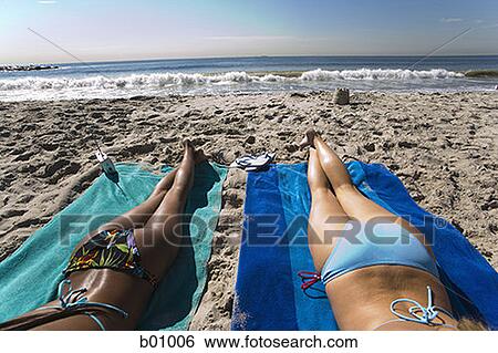 Rear view of two young women sunbathing on the beach View Large Photo Image Stock Photograph - Rear view of two young women sunbathing on the beach. Fotosearch