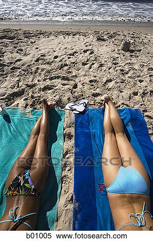 Rear view of two young women sunbathing on the beach View Large Photo Image Stock Photography - Rear view of two young women sunbathing on the beach. Fotosearch