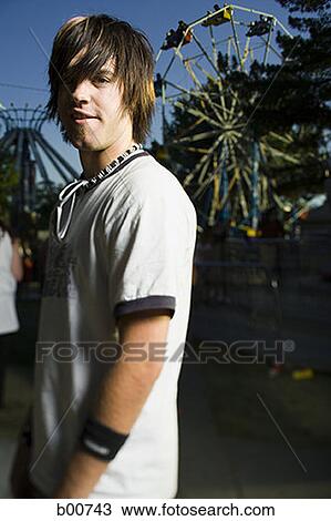 Side profile of a young man standing in an amusement park View Large Photo Image Stock Image - Side profile of a young man standing in an amusement park. Fotosearch