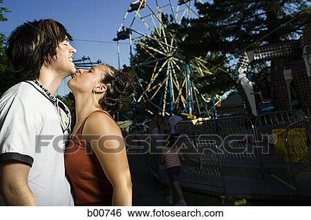Side profile of a young woman kissing a young man View Large Photo Image Stock Photograph - Side profile of a young woman kissing a young man. Fotosearch