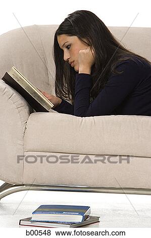 Side profile of a young woman lying on a couch and reading a book View Large Photo Image Stock Photo - Side profile of a young woman lying on a couch and reading a book. Fotosearch