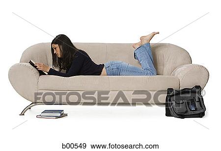 Side profile of a young woman lying on a couch and reading a book View Large Photo Image Stock Photo - Side profile of a young woman lying on a couch and reading a book. Fotosearch