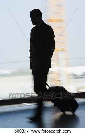 Silhouette of a businessman walking with a trolley View Large Photo Image Stock Photo - Silhouette of a businessman walking with a trolley. Fotosearch