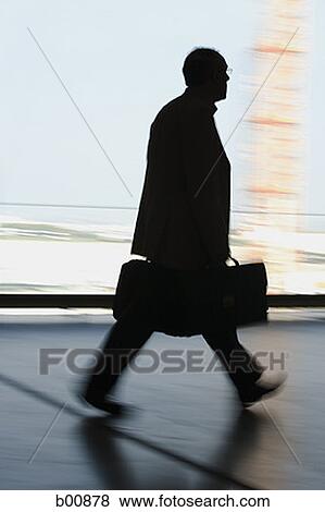 Silhouette of a businessman walking with a briefcase View Large Photo Image Stock Photo - Silhouette of a businessman walking with a briefcase. Fotosearch