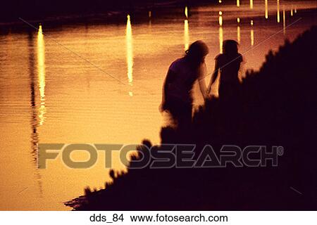 Silhouettes of two people on a riverbank View Large Photo Image Picture - Silhouettes of two people on a riverbank. Fotosearch
