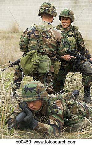 Soldier aiming his rifle with two soldiers talking behind him View Large Photo Image Stock Photo - Soldier aiming his rifle with two soldiers talking behind him. Fotosearch