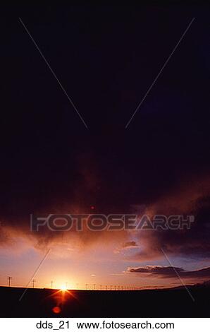 Stock Image - Storm clouds over a landscape at sunset. Fotosearch