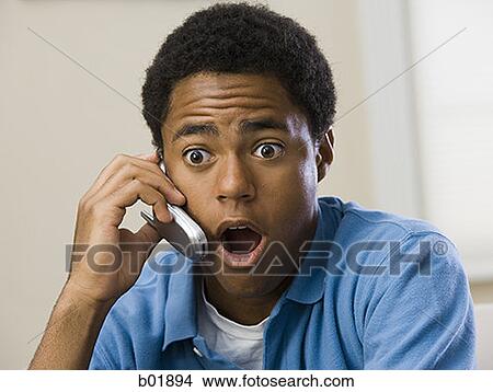 Teenage boy on a mobile phone with his mouth open, looking surprised View Large Photo Image Picture - Teenage boy on a mobile phone with his mouth open, looking surprised. Fotosearch