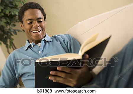 Teenage boy reading a book and smiling View Large Photo Image Stock Photo - Teenage boy reading a book and smiling. Fotosearch