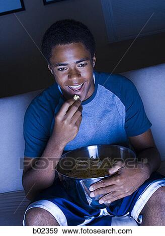 Teenage boy watching television and eating popcorn View Large Photo Image Stock Photo - Teenage boy watching television and eating popcorn. Fotosearch