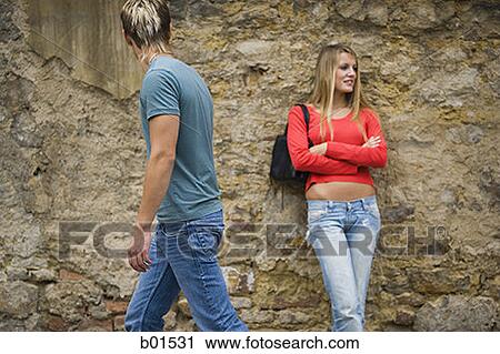 Teenage girl leaning against a wall with a teenage boy looking at her View Large Photo Image Stock Image - Teenage girl leaning against a wall with a teenage boy looking at her. Fotosearch