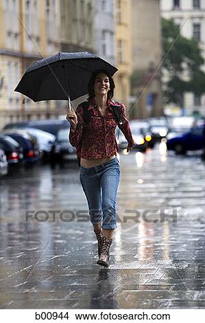 Teenage girl walking in the rain with an umbrella View Large Photo Image Picture - Teenage girl walking in the rain with an umbrella. Fotosearch