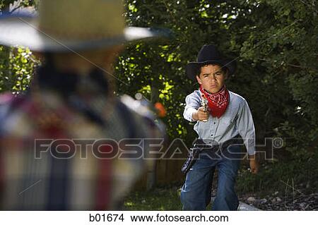 Two boys in cowboy costumes aiming each other with a toy gun View Large Photo Image Picture - Two boys in cowboy costumes aiming each other with a toy gun. Fotosearch