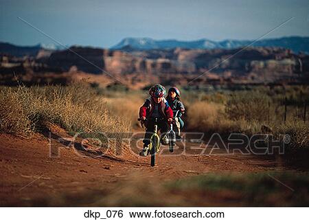 Two children cycling in a desert View Large Photo Image Stock Photograph - Two children cycling in a desert. Fotosearch
