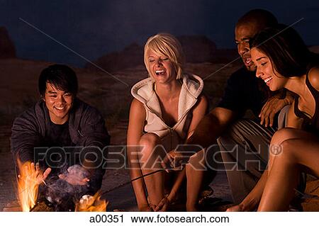 Two couples sitting by a campfire View Large Photo Image Stock Image - Two couples sitting by a campfire. Fotosearch