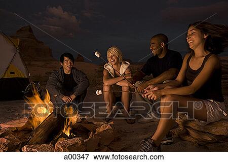 Two couples sitting by a campfire View Large Photo Image Stock Photo - Two couples sitting by a campfire. Fotosearch