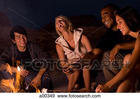 Two couples sitting by a campfire View Large Photo Image Stock Photo - Two couples sitting by a campfire. Fotosearch