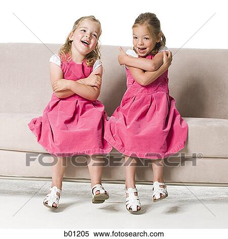 Stock Photography - Two girls sitting side by side on a couch. Fotosearch