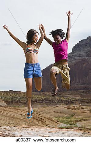 Two young women jumping in air View Large Photo Image Stock Photo - Two young women jumping in air. Fotosearch