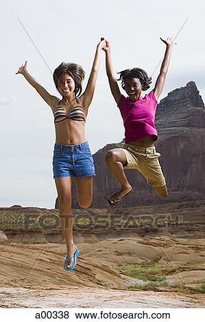 Two young women jumping in air View Large Photo Image Stock Photo - Two young women jumping in air. Fotosearch