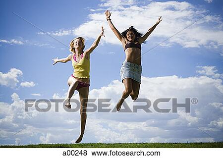 Two young women jumping View Large Photo Image Stock Photo - Two young women jumping . Fotosearch